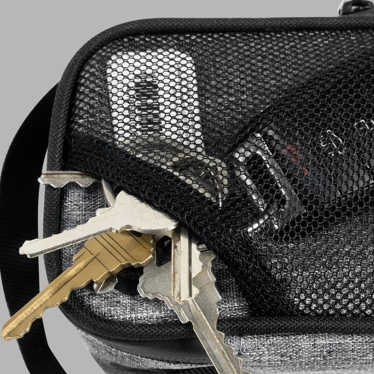 Mesh zippered pocket with keys, lighter, and key fob on a grey fabric bag