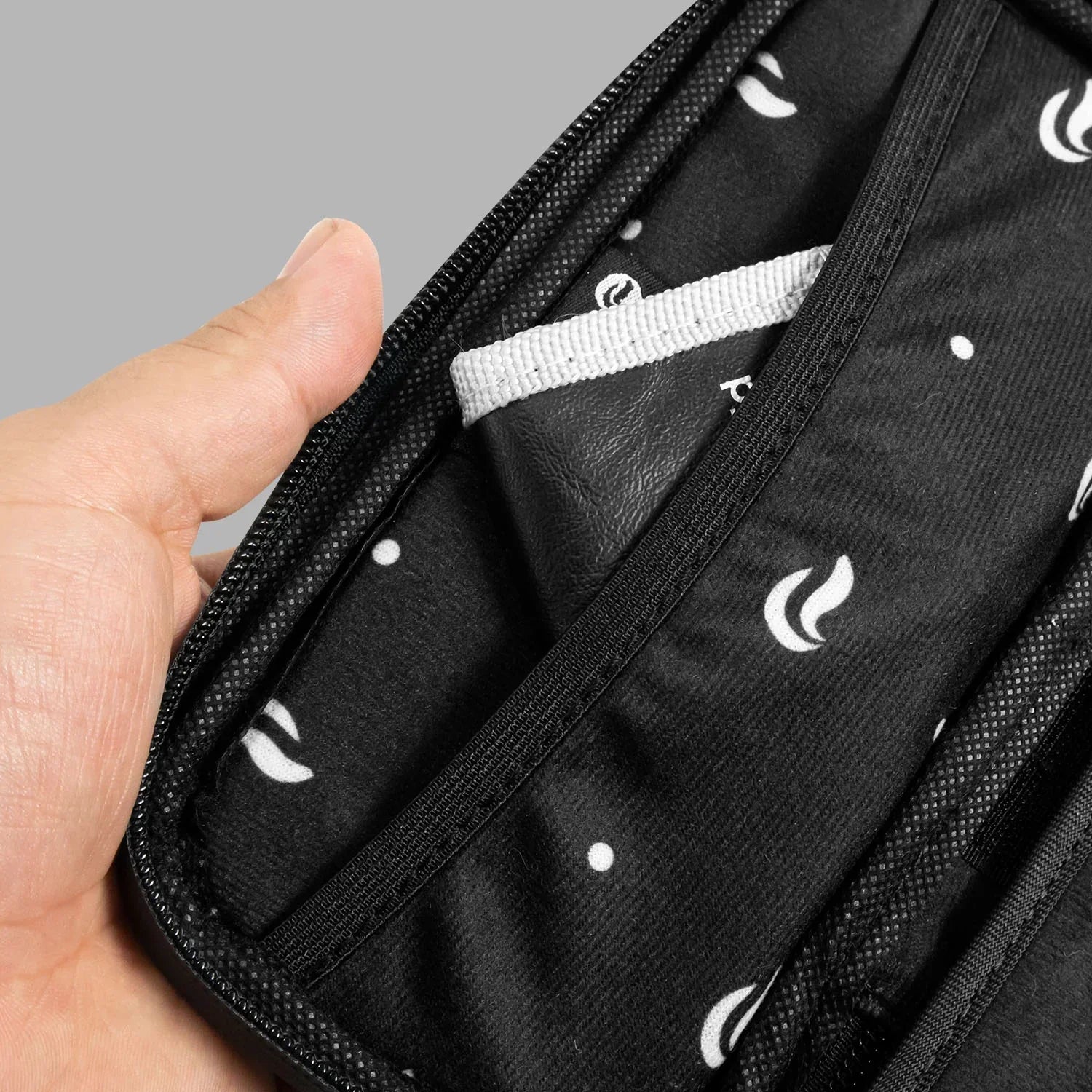 Hand holding open padded black carrying case with patterned lining and inner pocket
