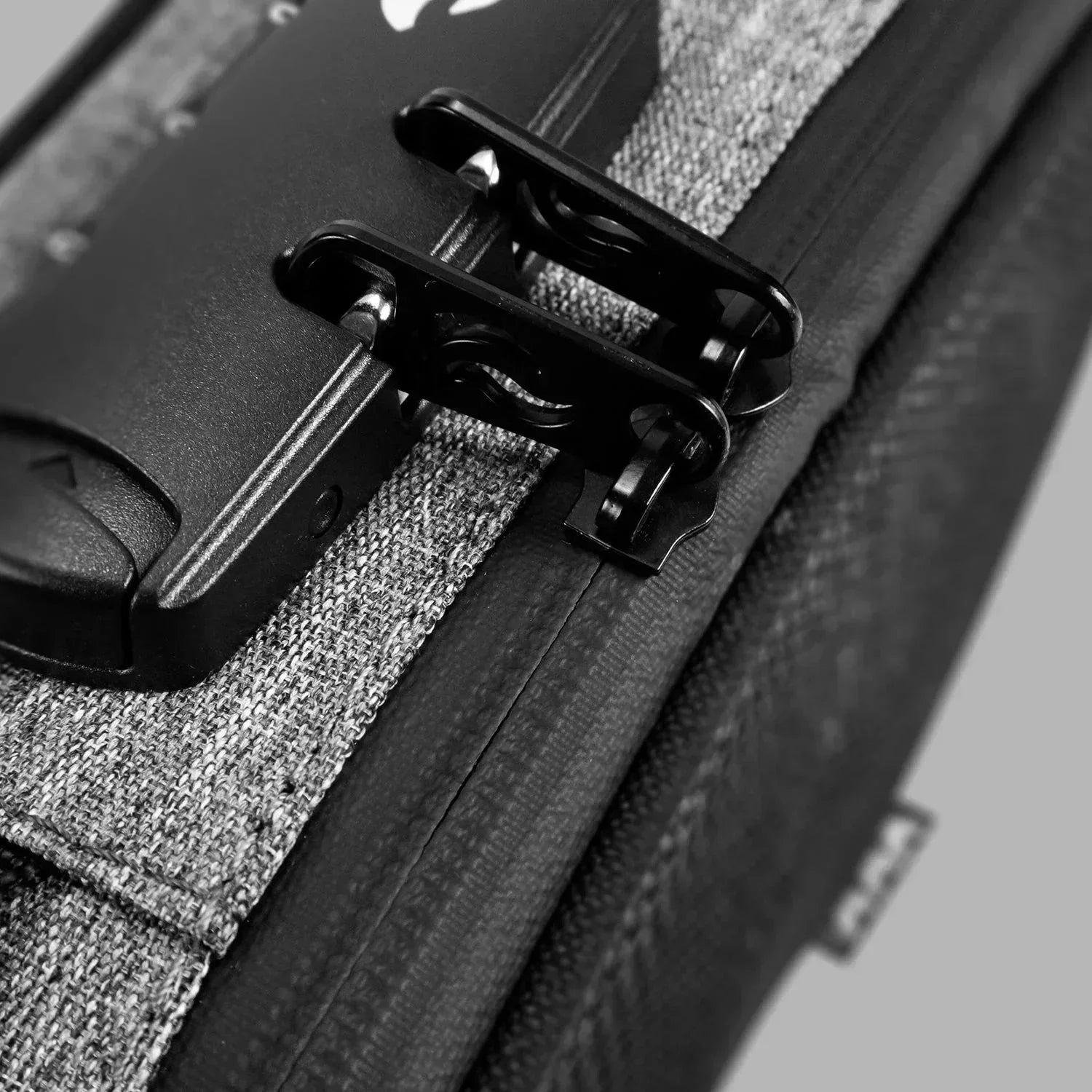Close-up of a gray fabric bag with black zipper pulls and integrated lock
