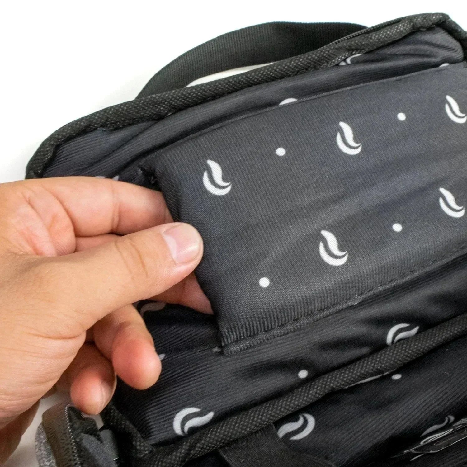 Hand opening gray duffle bag with padded, patterned interior pocket.