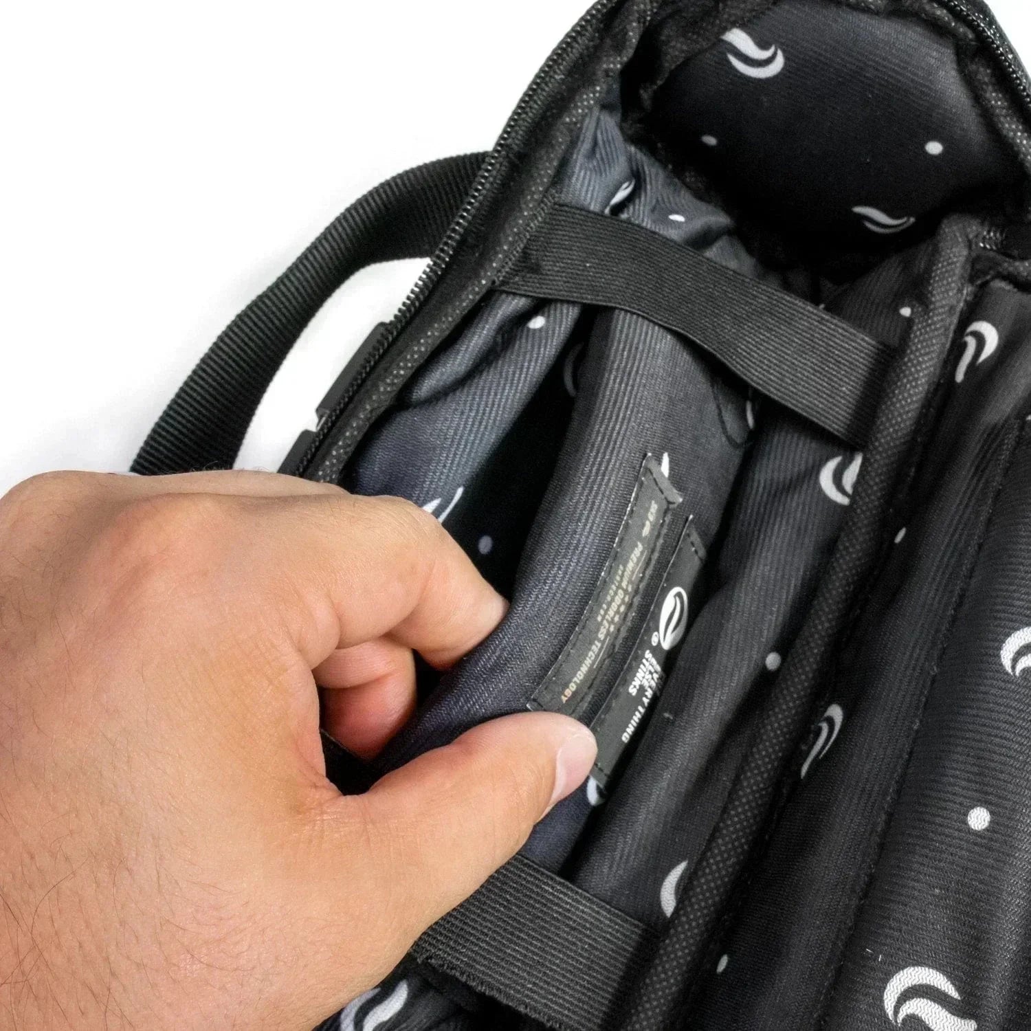 Hand opening padded pocket inside gray duffle bag with black and white patterned lining