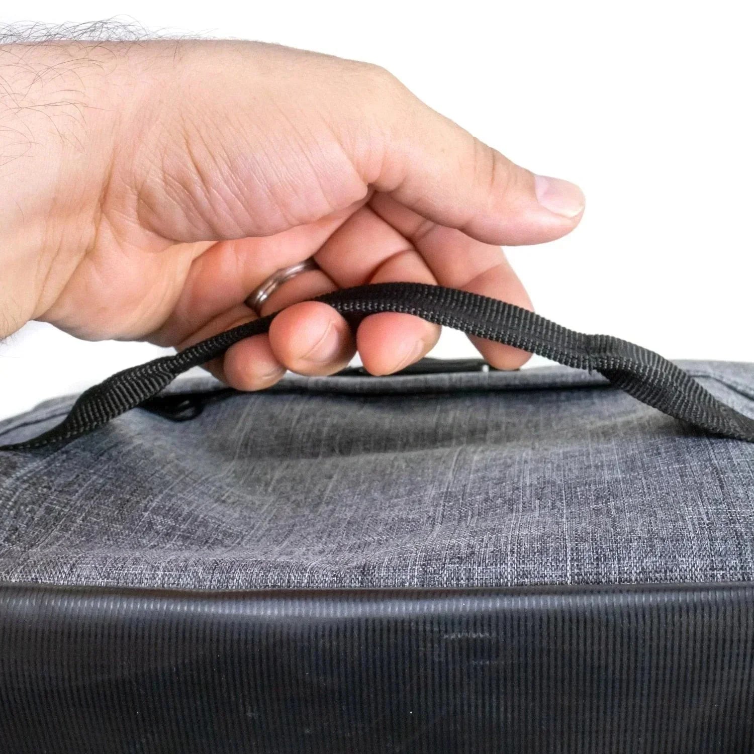 Hand holding black and gray carrying case with fabric handle and textured surface