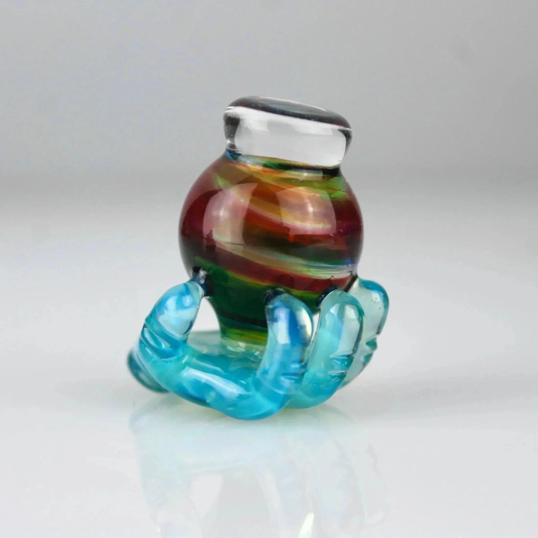 Hand-blown glass carb cap with colorful rainbow stripes and blue hand-shaped base.