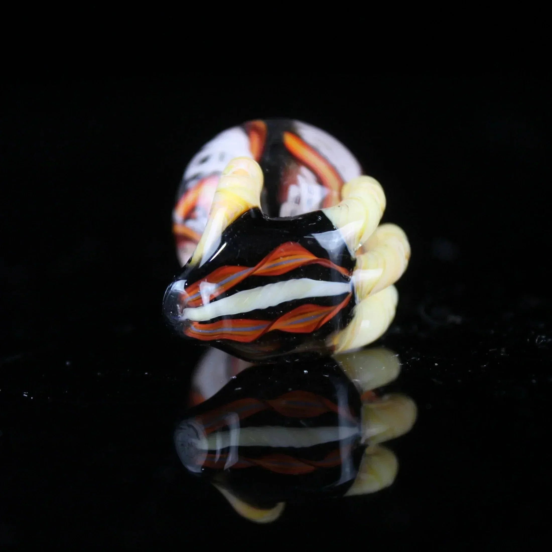 Handcrafted glass marble with desert night colors, fine line latticino design on black background