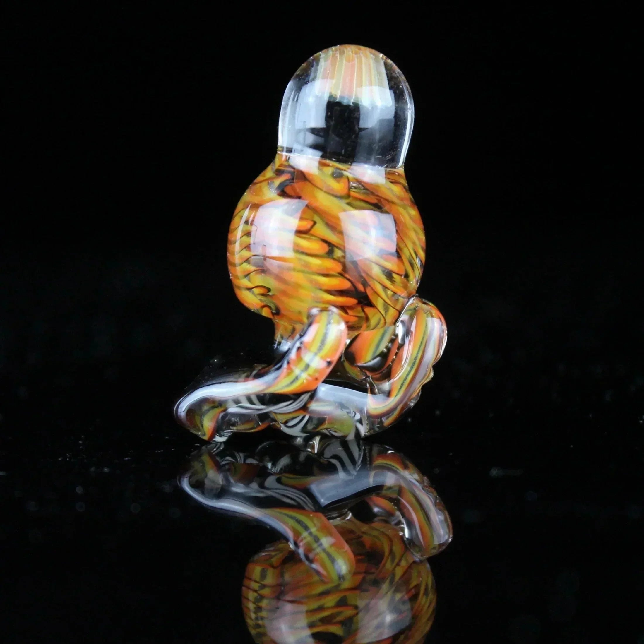 Multicolored glass carb cap with orange and yellow pattern on black background