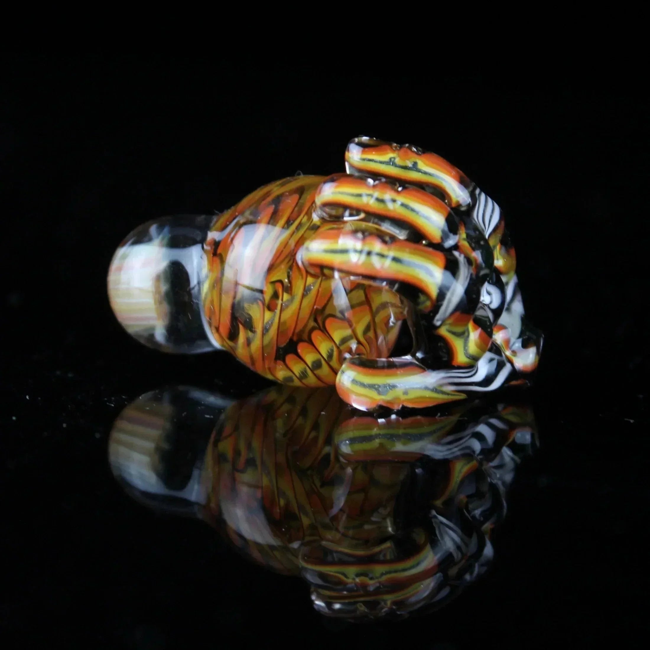 Hand-blown glass dab accessory with orange and yellow striped design on black background