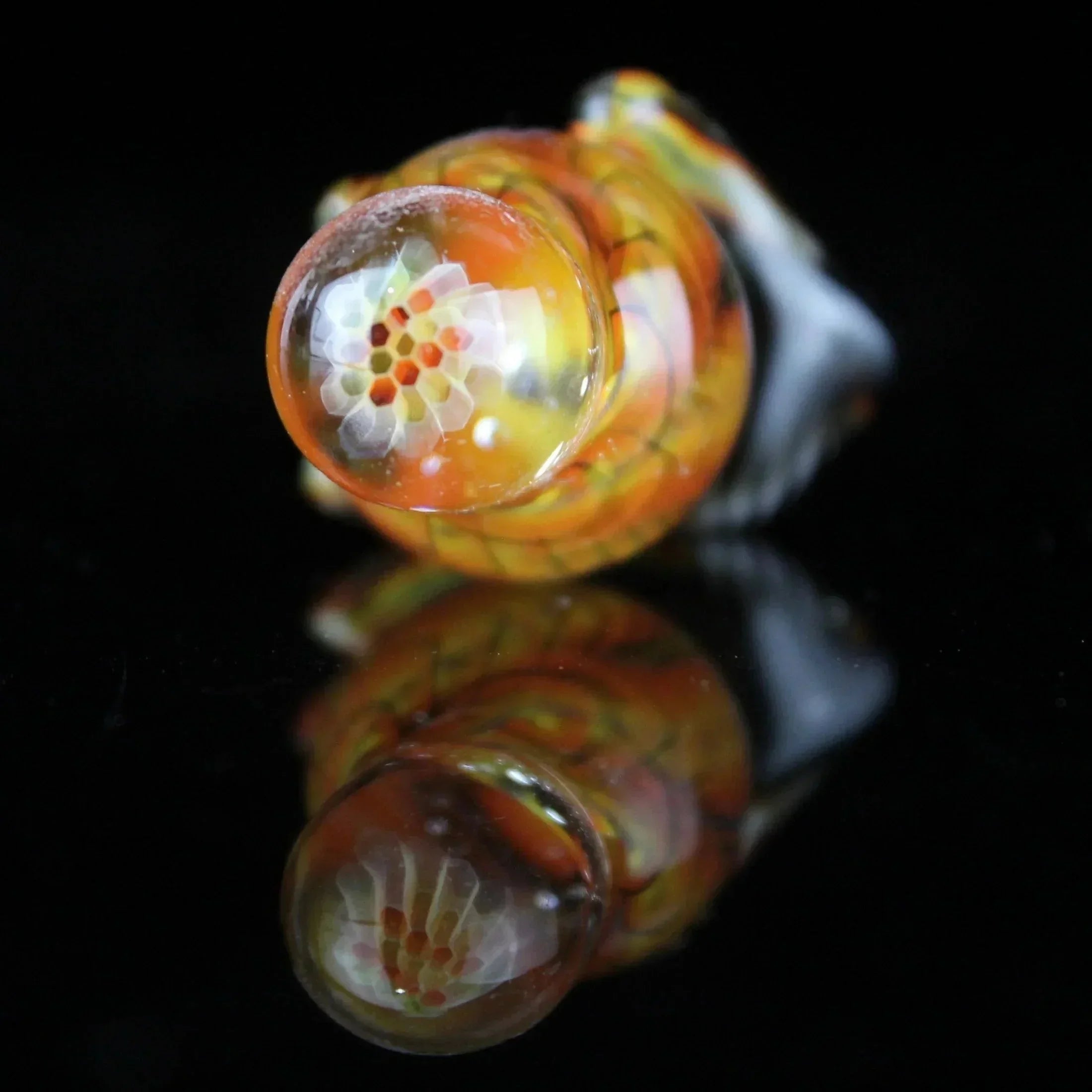 Colorful glass terp slurper marble with intricate honeycomb pattern on black background