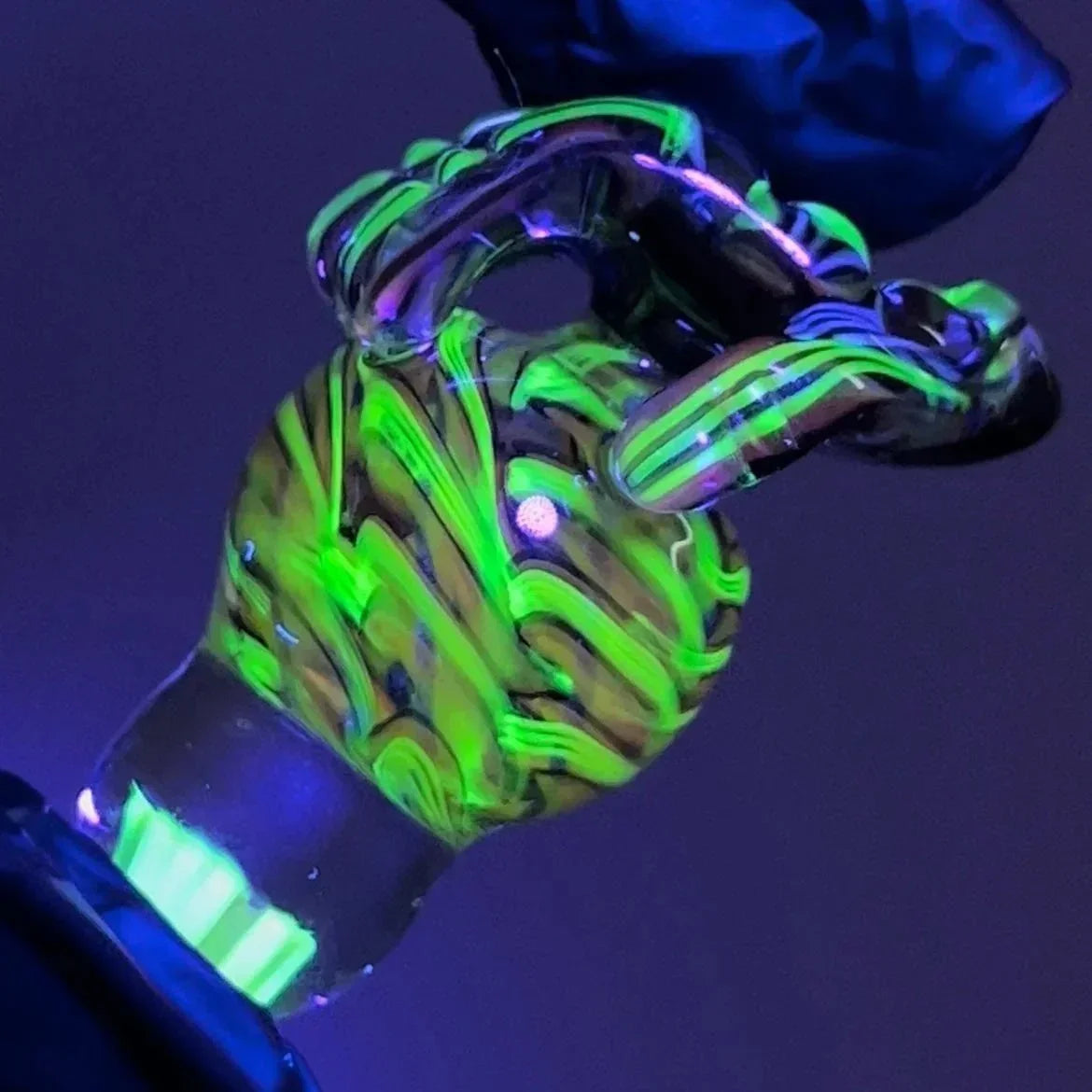 UV reactive glass smoking accessory with neon green and black swirl pattern under blacklight