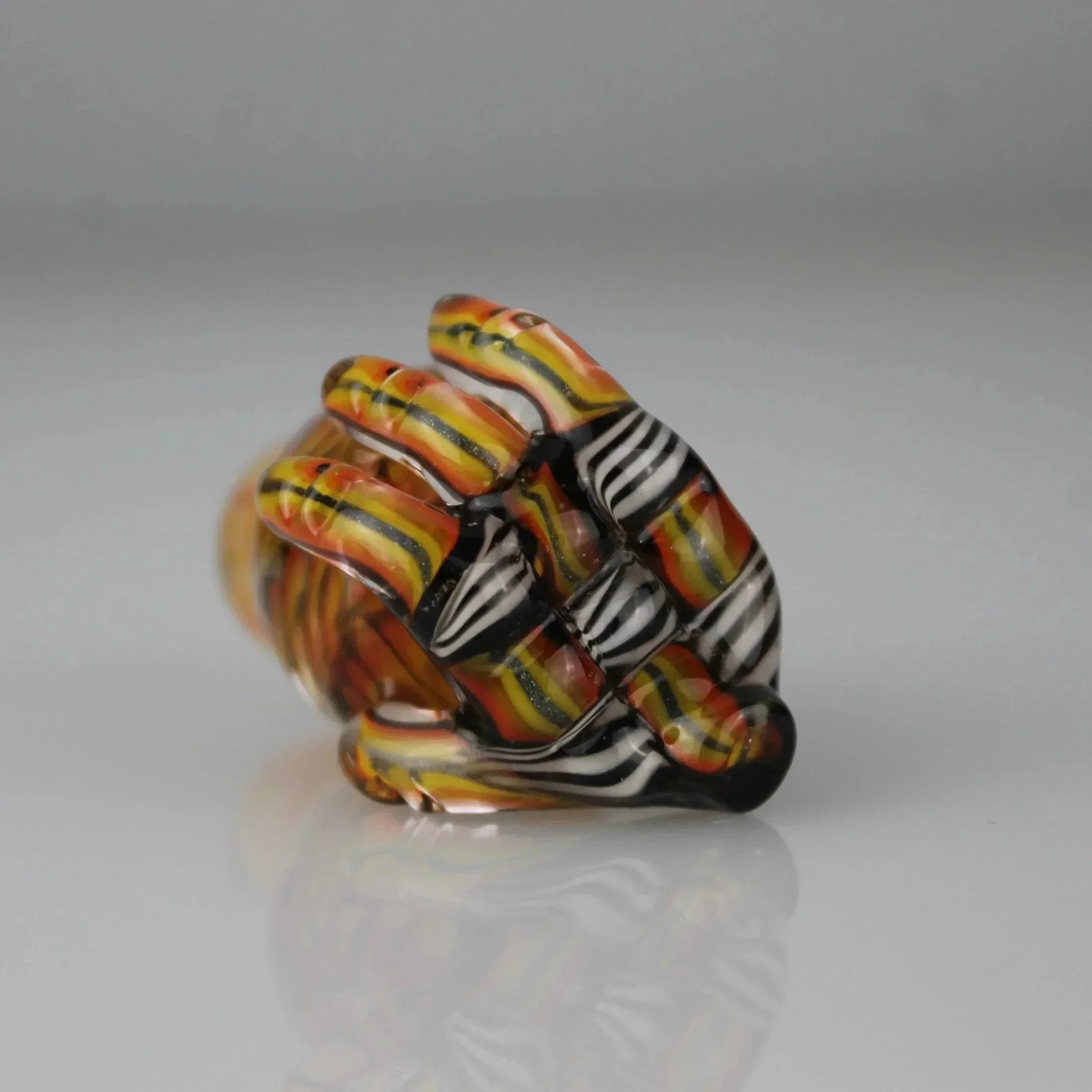 Handcrafted glass accessory with orange, yellow, black, and white striped pattern