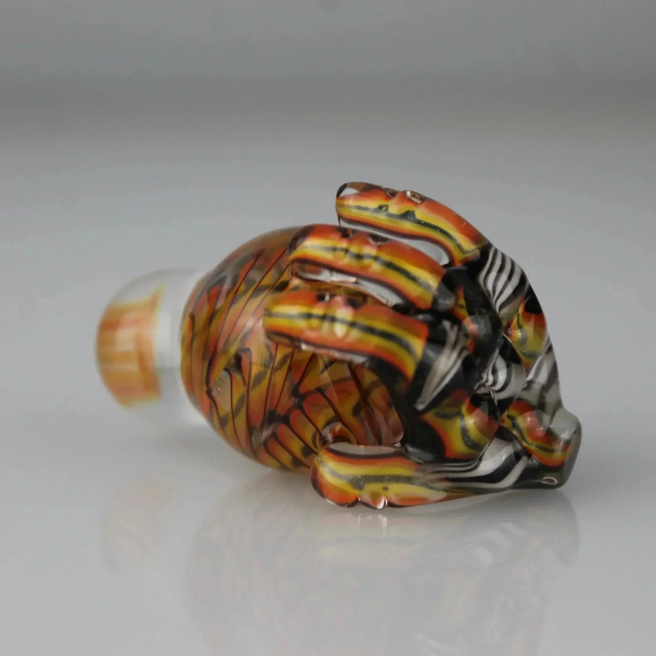 Handcrafted glass slurper marble with orange, yellow, black chip weave pattern on gray background