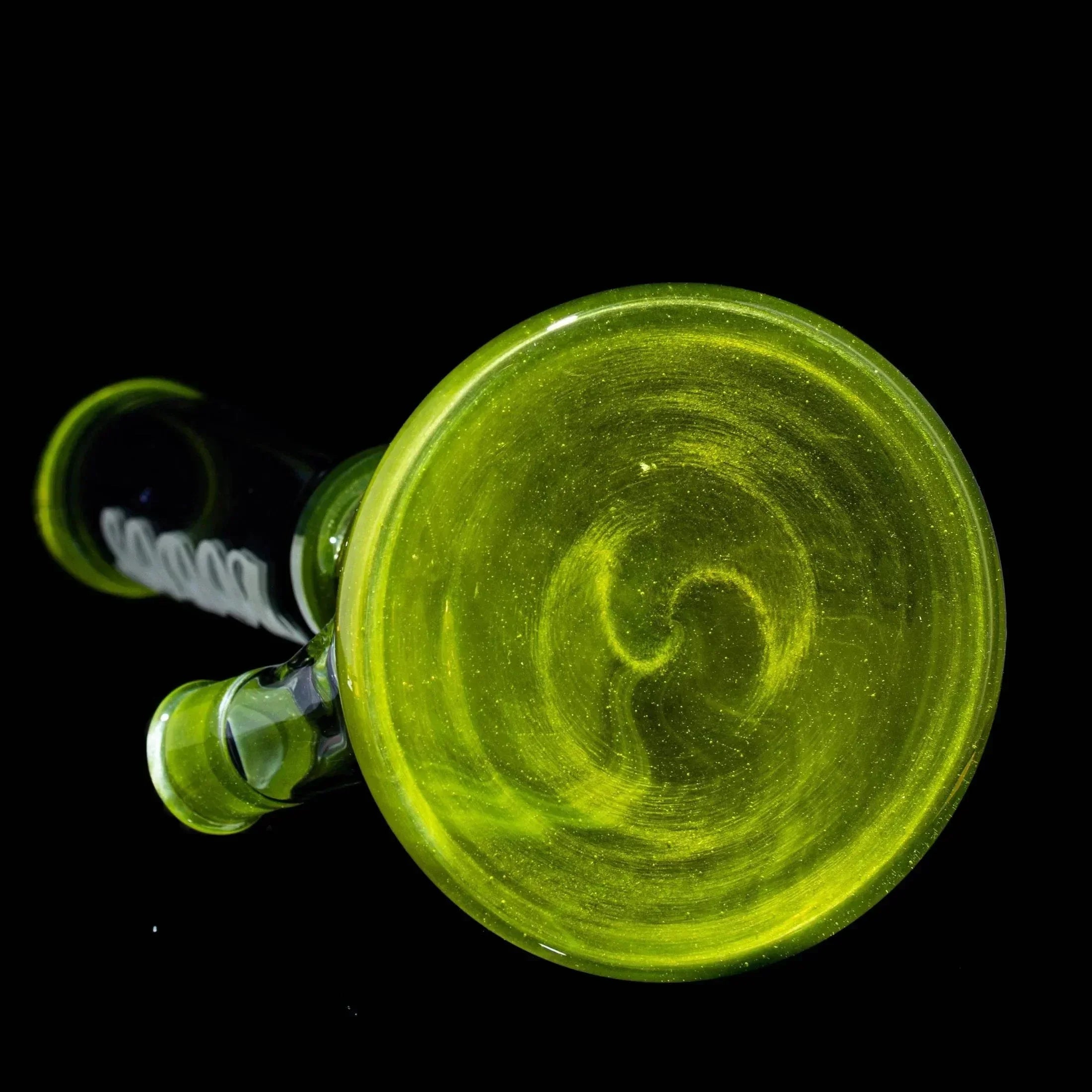 Green glass pipe with swirled base, viewed from above on a black background