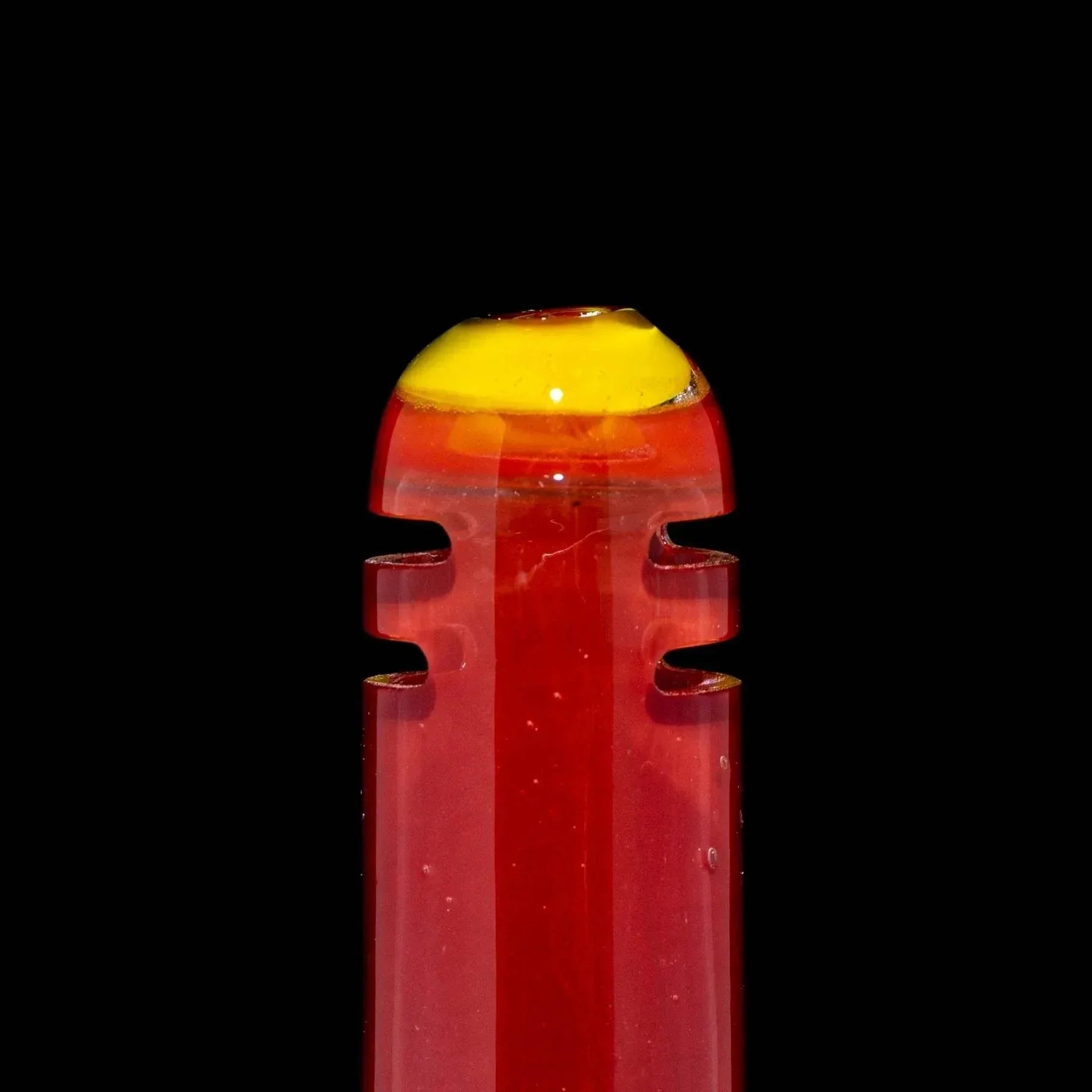 Red and yellow glass accessory with notched sides on a black background
