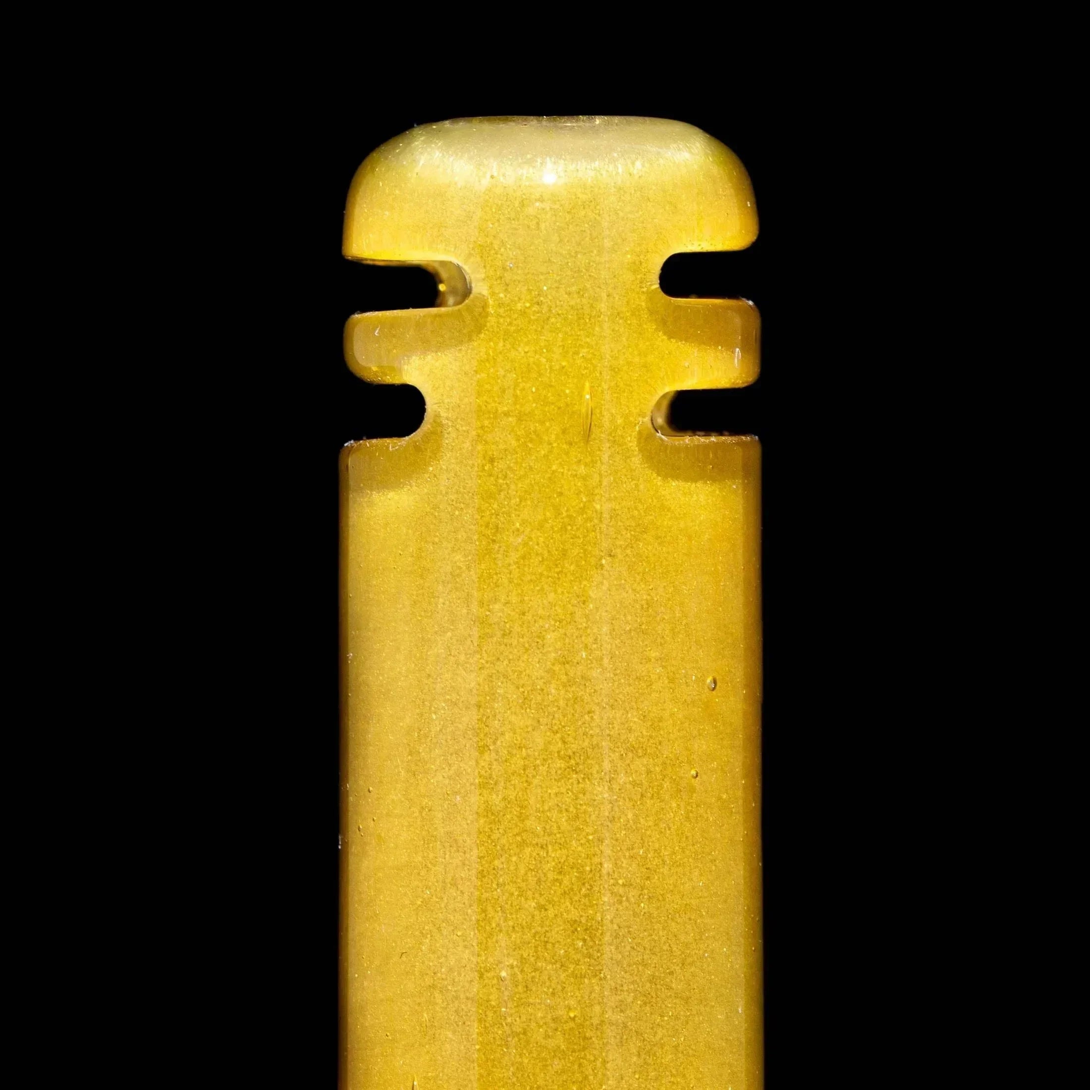 Close-up of a peach satin glass pipe accessory with grooved details on black background