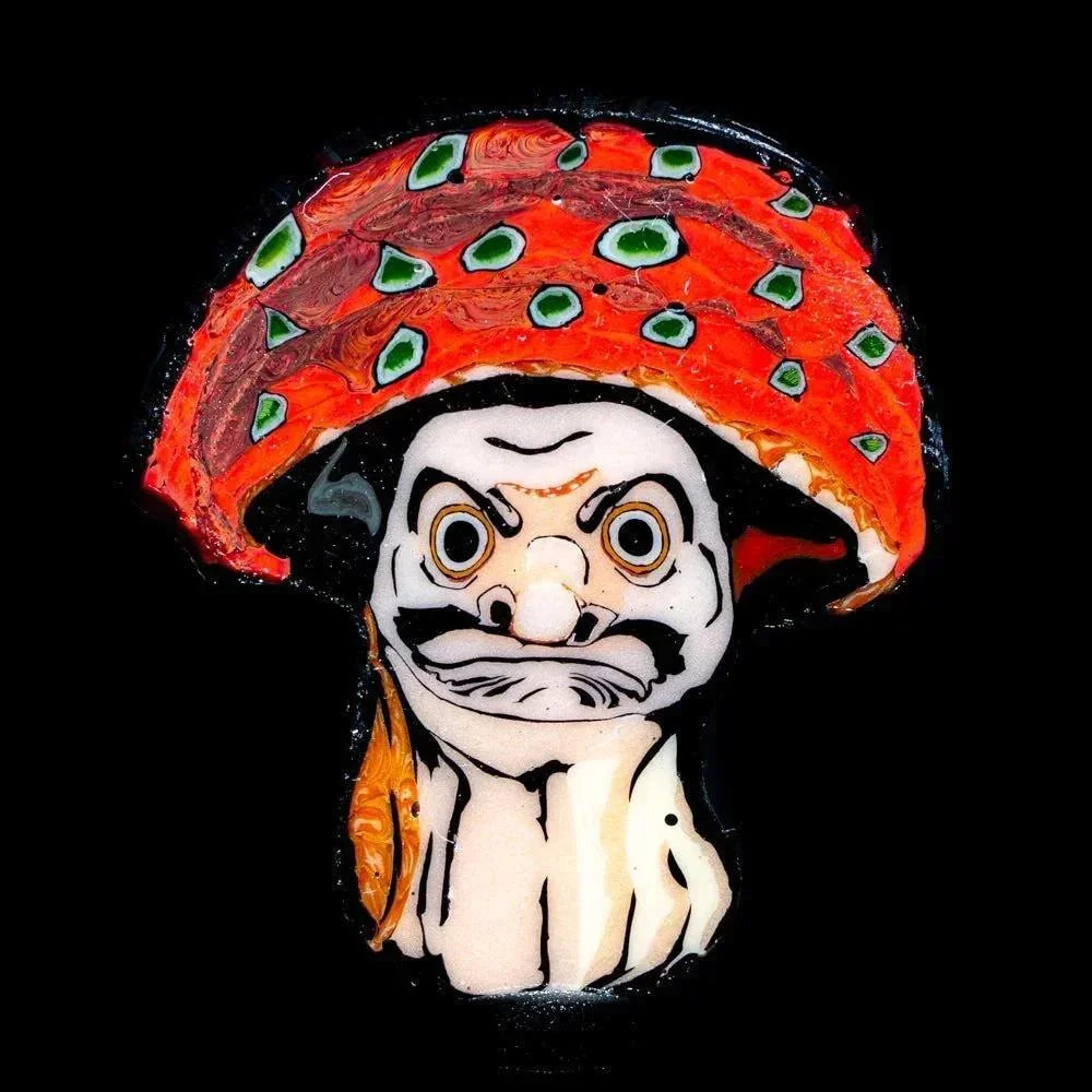 Handcrafted glass coin featuring a Daruma-inspired face with a colorful red mushroom cap