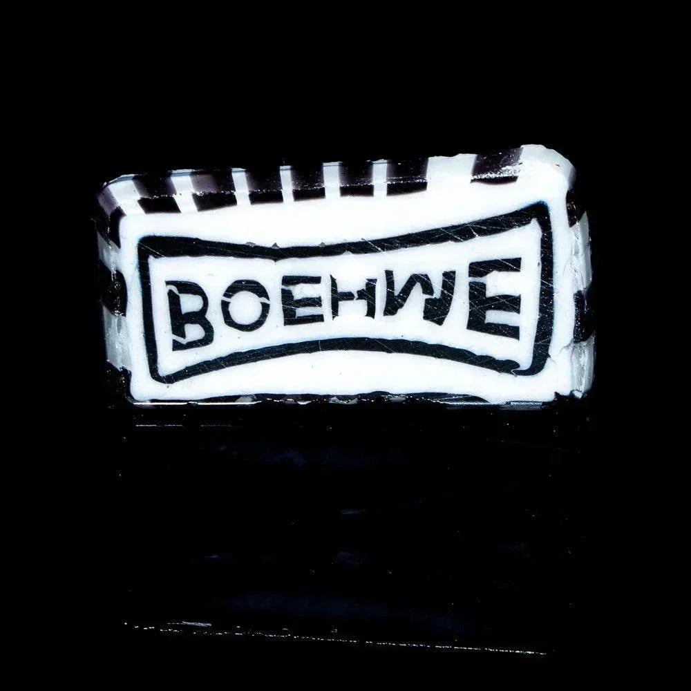 Rectangular black and white glass coin with BOEHME text, striped border, on black background
