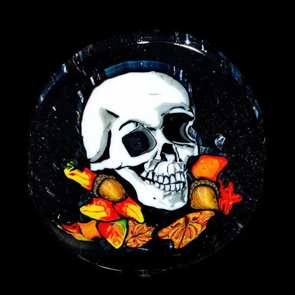 Glass coin featuring a white skull with colorful autumn leaves on a black background