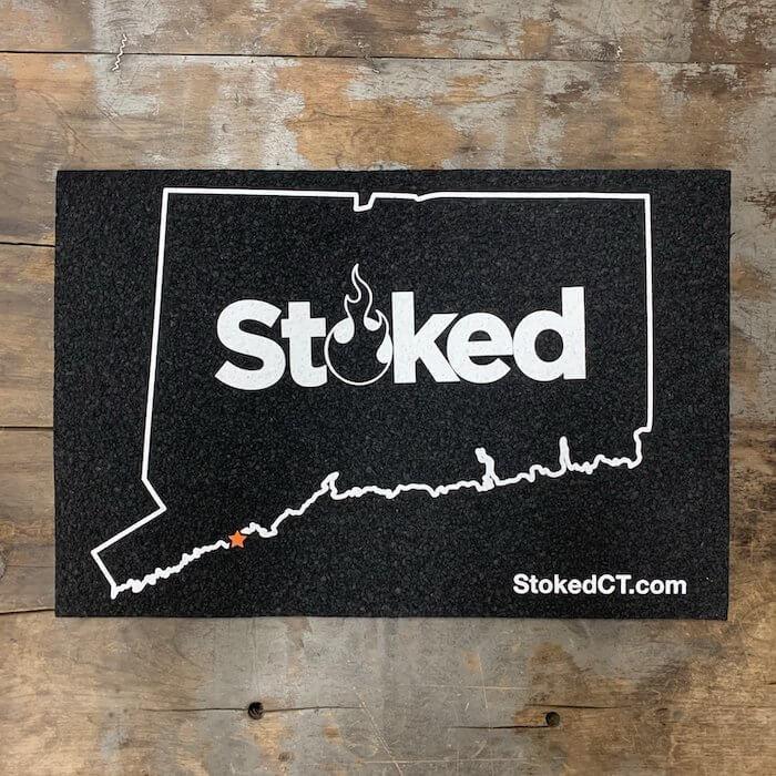 Stoked CT doormat with Connecticut state outline, flame logo, and StokedCT.com text on black mat