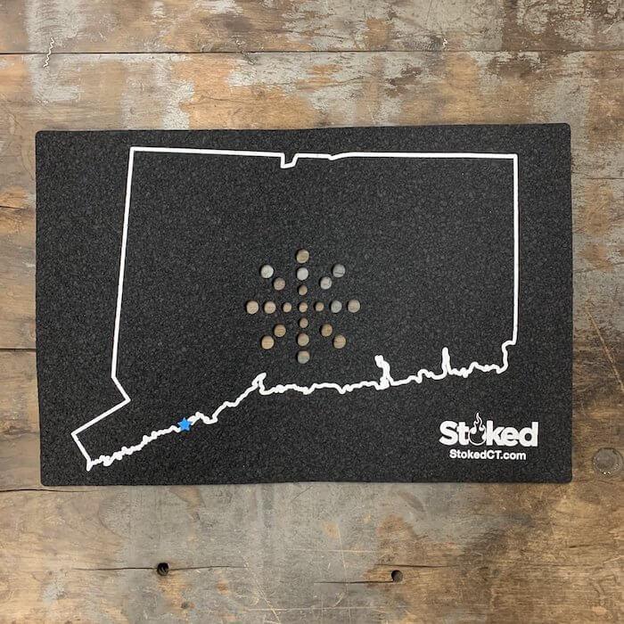 Black Connecticut state outline mat with white border, star marker, and Stoked logo, displayed on wood floor