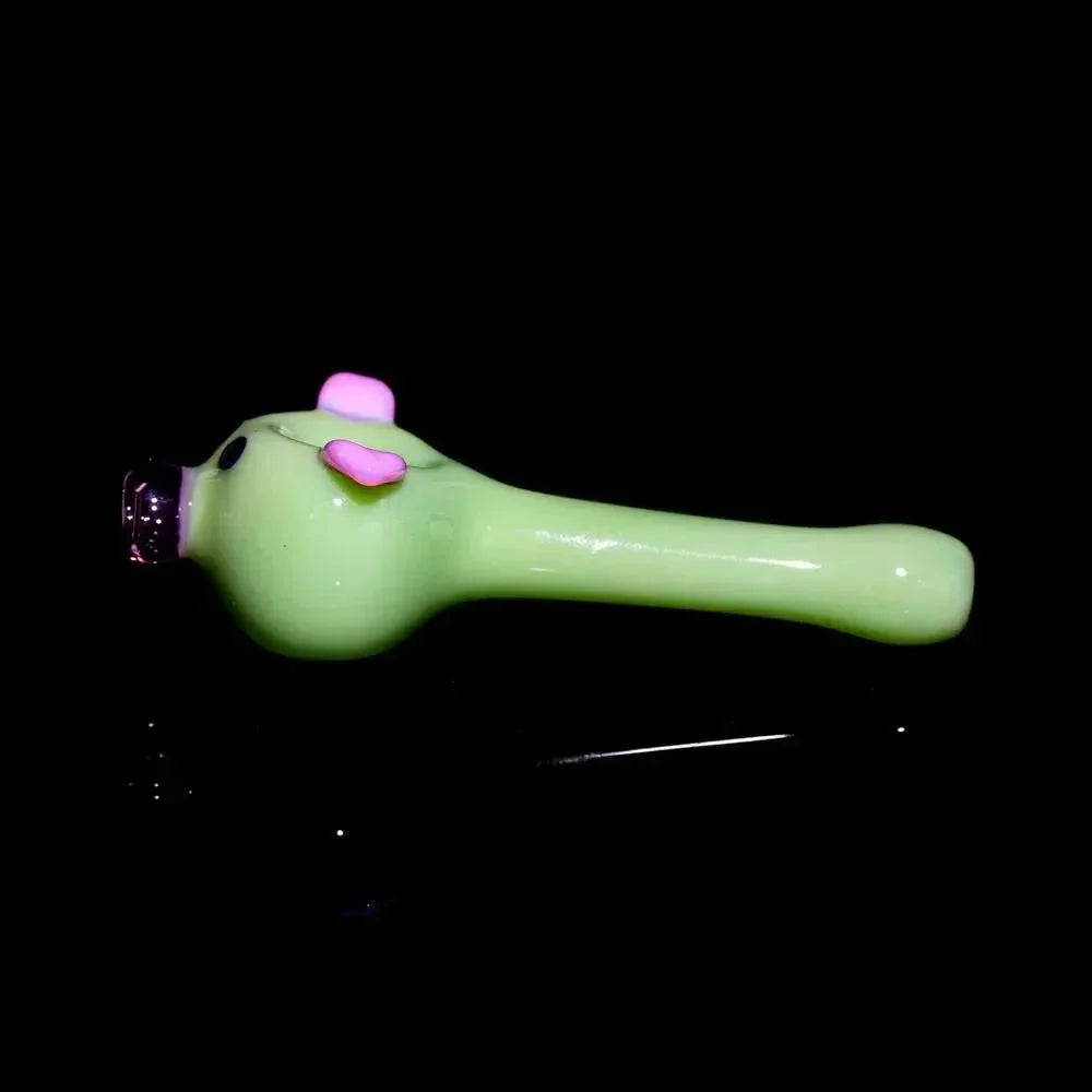 Milky green glass hand pipe shaped like a pig with pink ears on black background