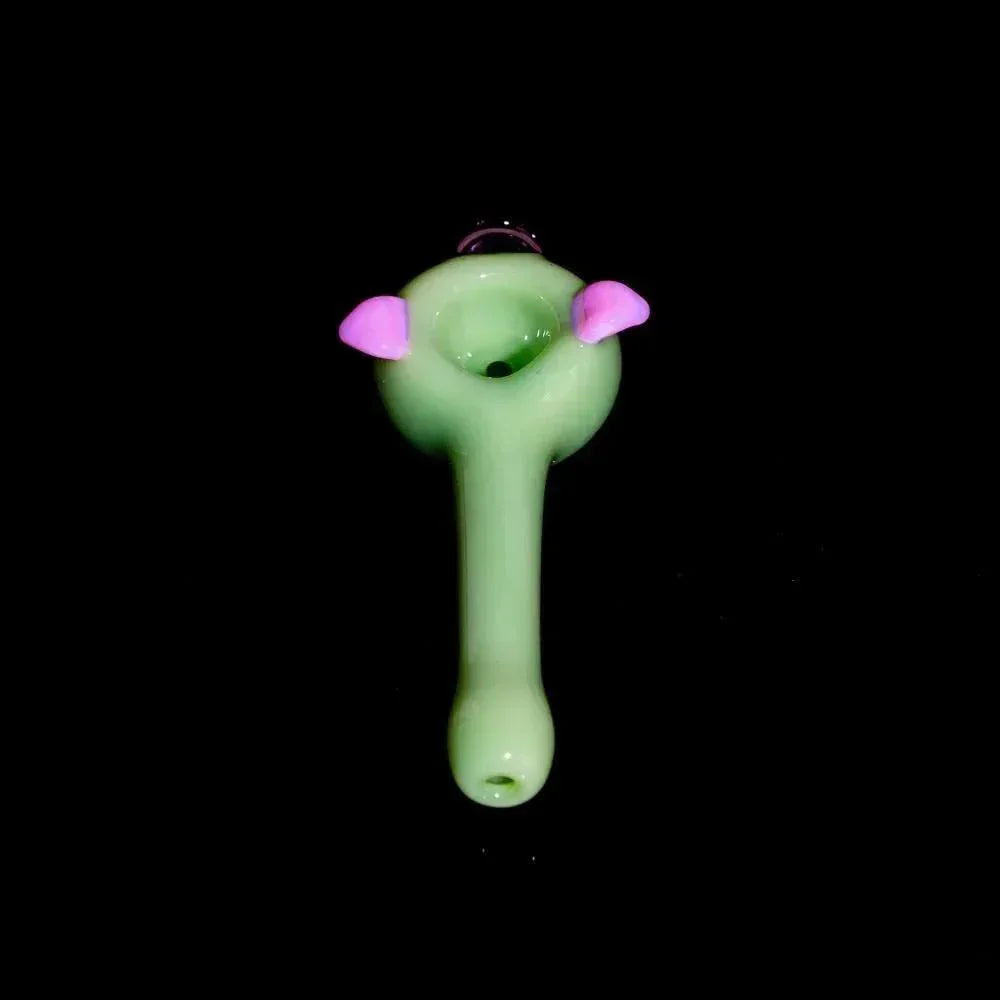 Milky green glass hand pipe with piggy design and pink ears on a black background