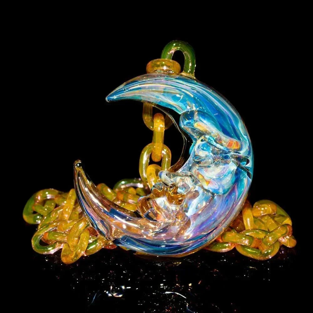 Iridescent glass crescent moon pendant with face detail and yellow chain on black background