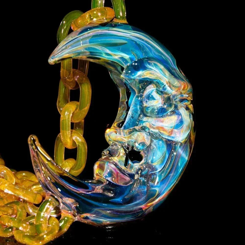 Handcrafted blue glass moon pendant with face detail on a yellow glass chain, black background