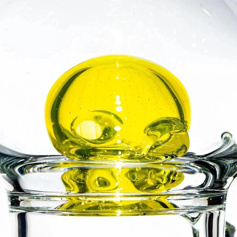 Close-up of a yellow glass bubble accent inside a clear glass water pipe