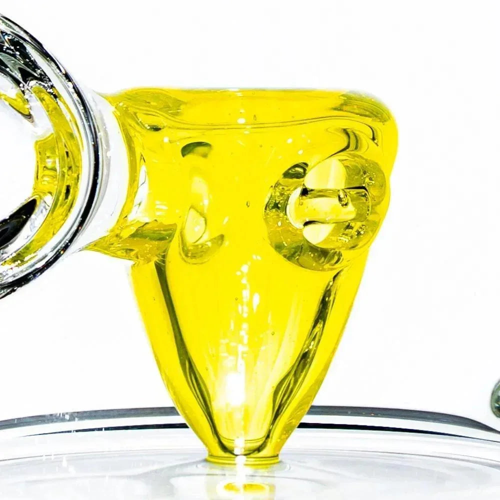 Close-up of a yellow glass water pipe bowl with intricate design on a clear base