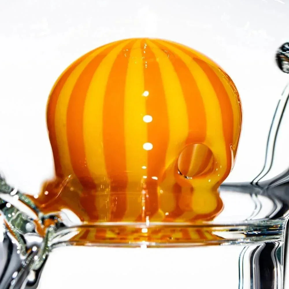 Orange and yellow striped glass carb cap for dab rig on clear glass surface