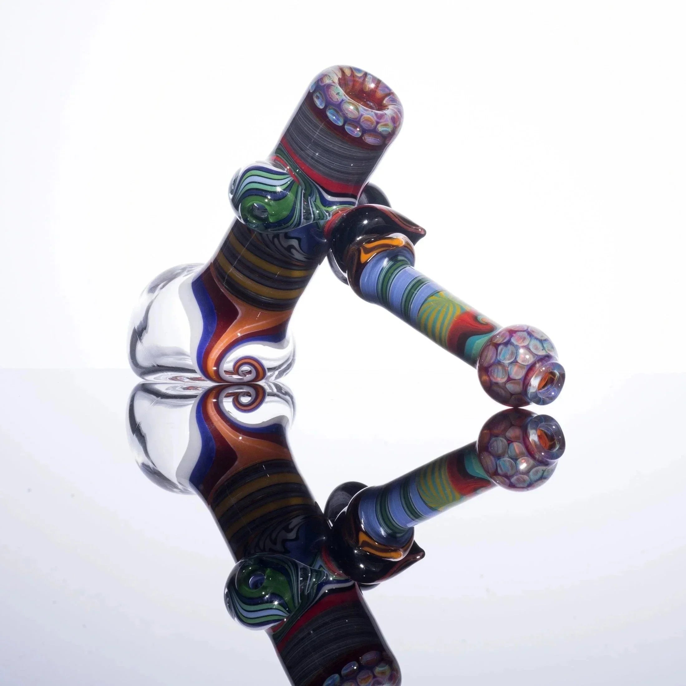 Colorful glass bubbler pipe with intricate patterns and reflection on white background
