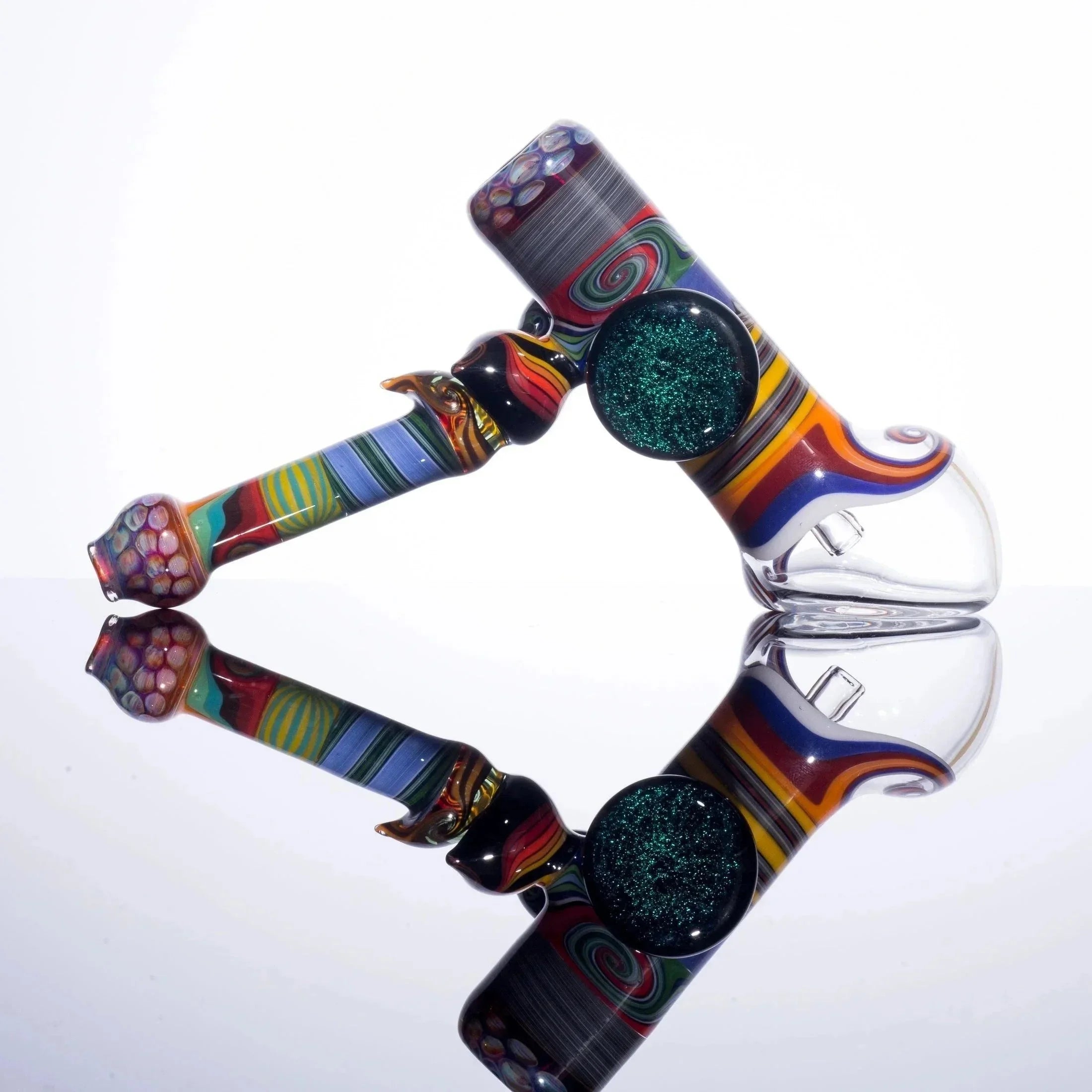 Colorful glass bubbler pipe with swirling patterns and glitter detail on reflective surface