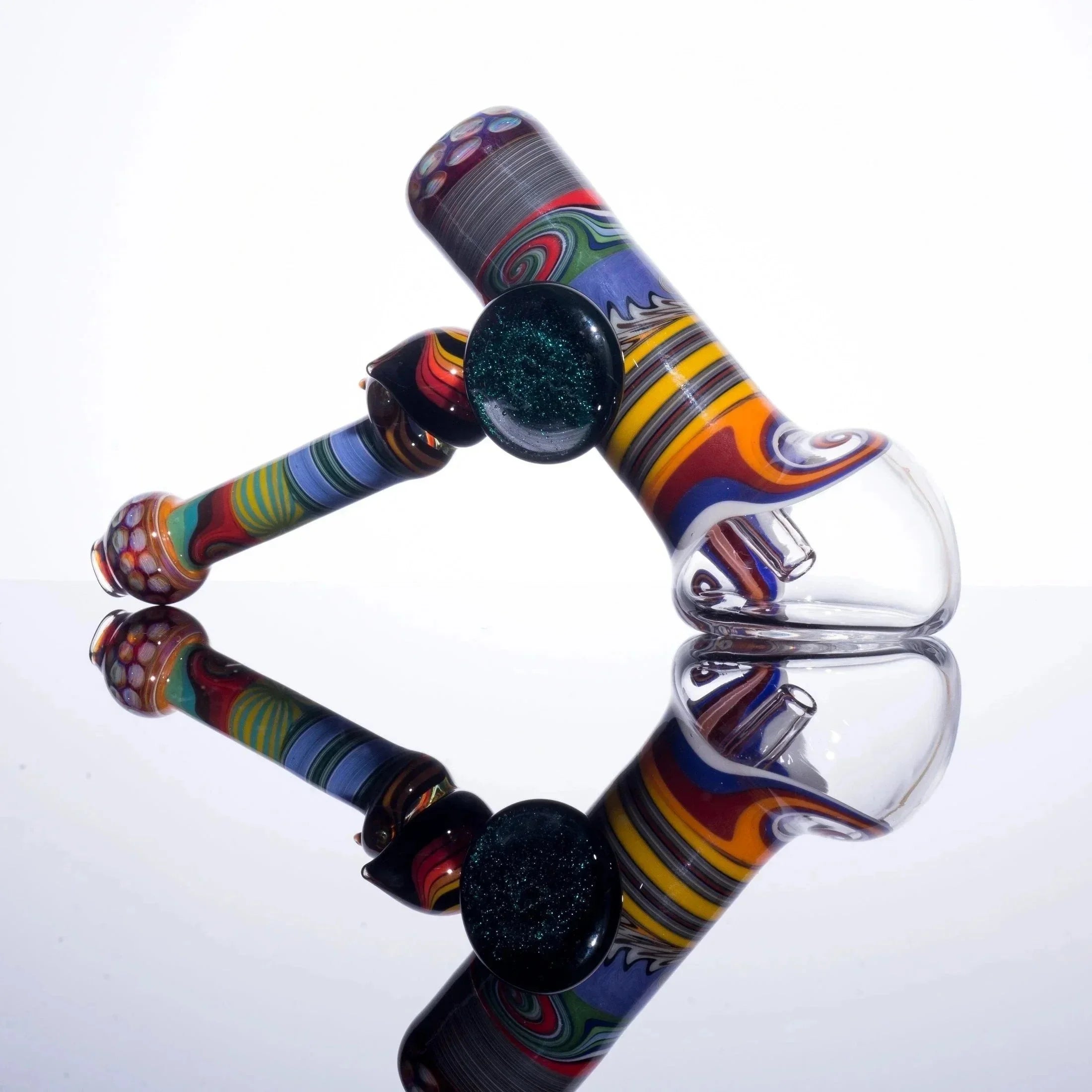Colorful glass bubbler pipe with intricate swirls and marbles, reflected on glossy surface