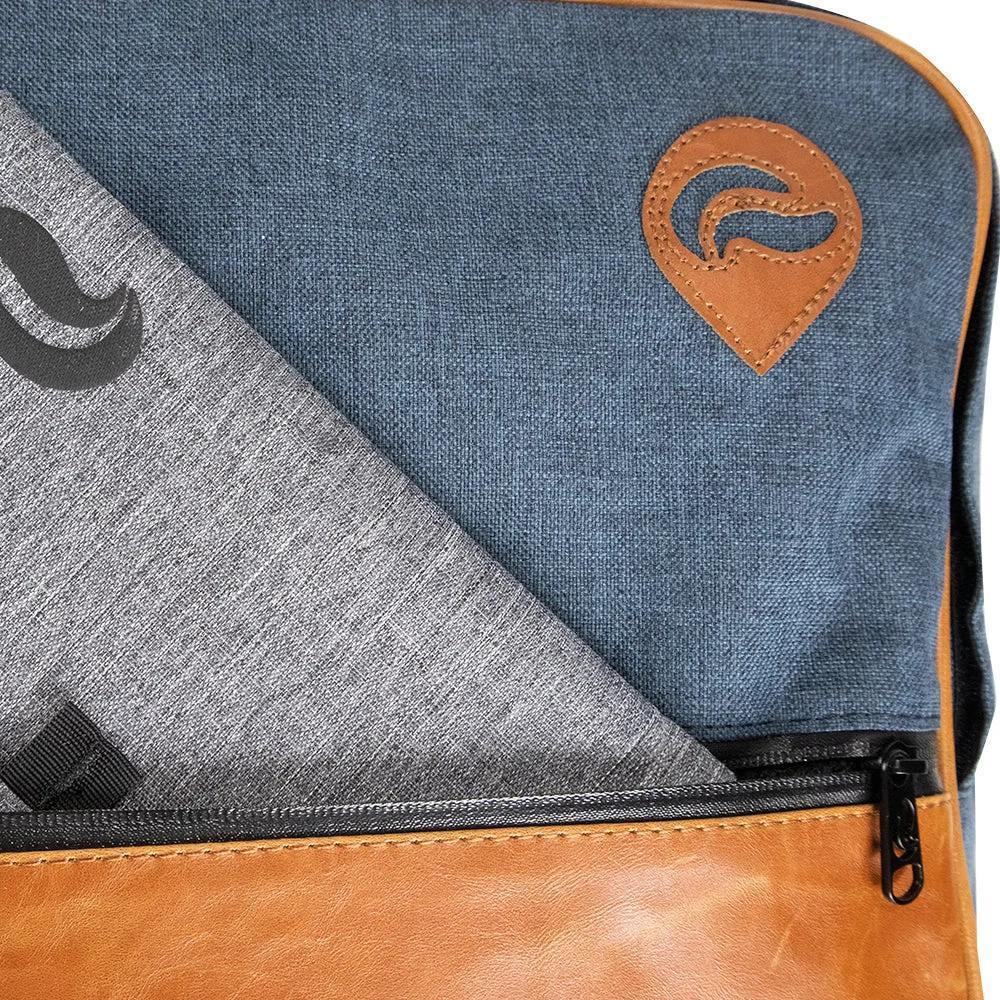 Closeup of a blue and brown backpack with zippered front pocket and leather logo patch