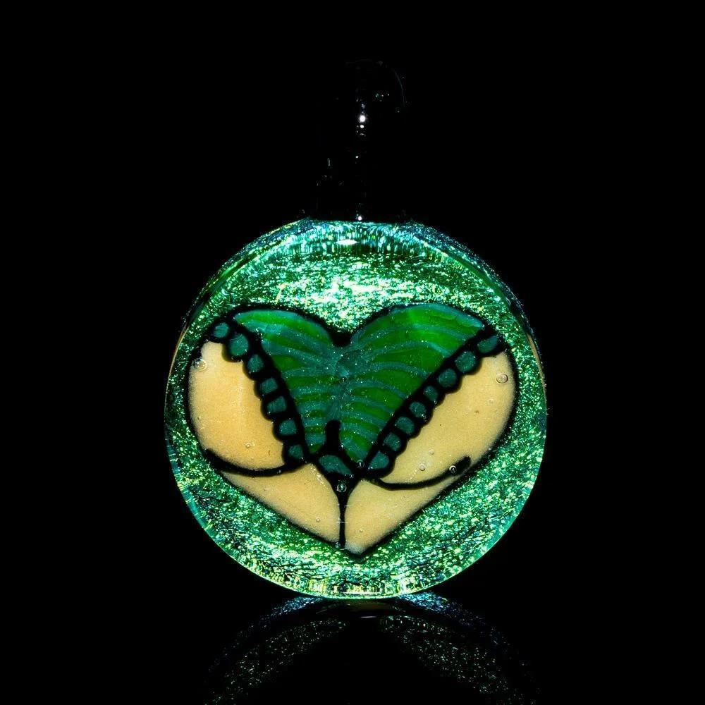 Handcrafted glass pendant with green and beige abstract design, glittery finish, on black background.