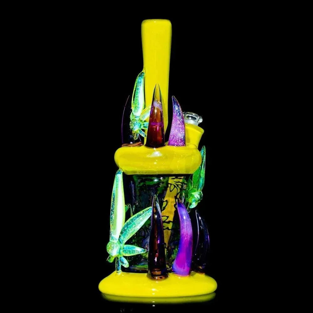 Heady glass water pipe with yellow base, colorful spikes, and decorative leaf accents