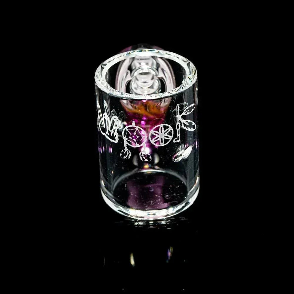 Clear glass smoking accessory with etched designs and purple accents on black background