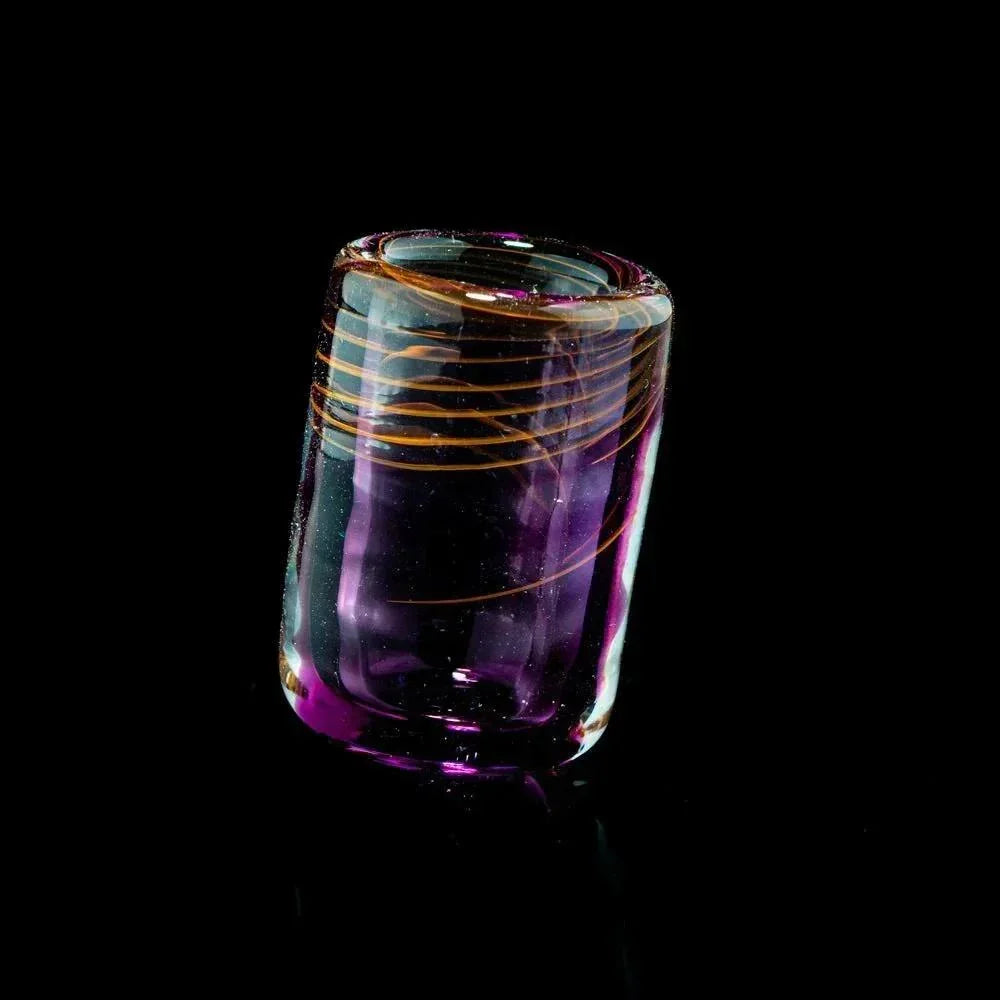 Hand-blown glass accessory with purple tint and orange swirl design on black background