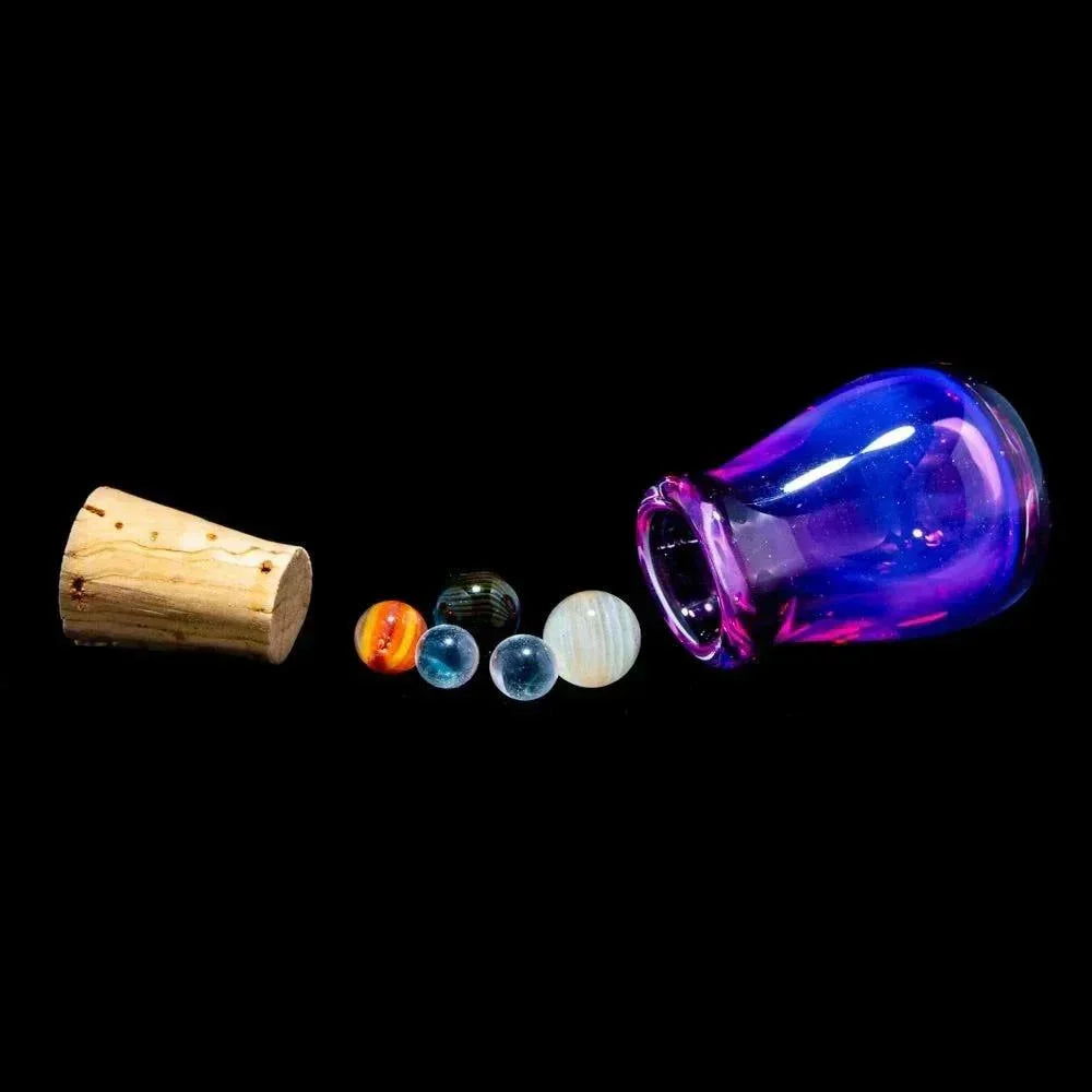 Mini planet glass marbles set with cork and purple jar on black background