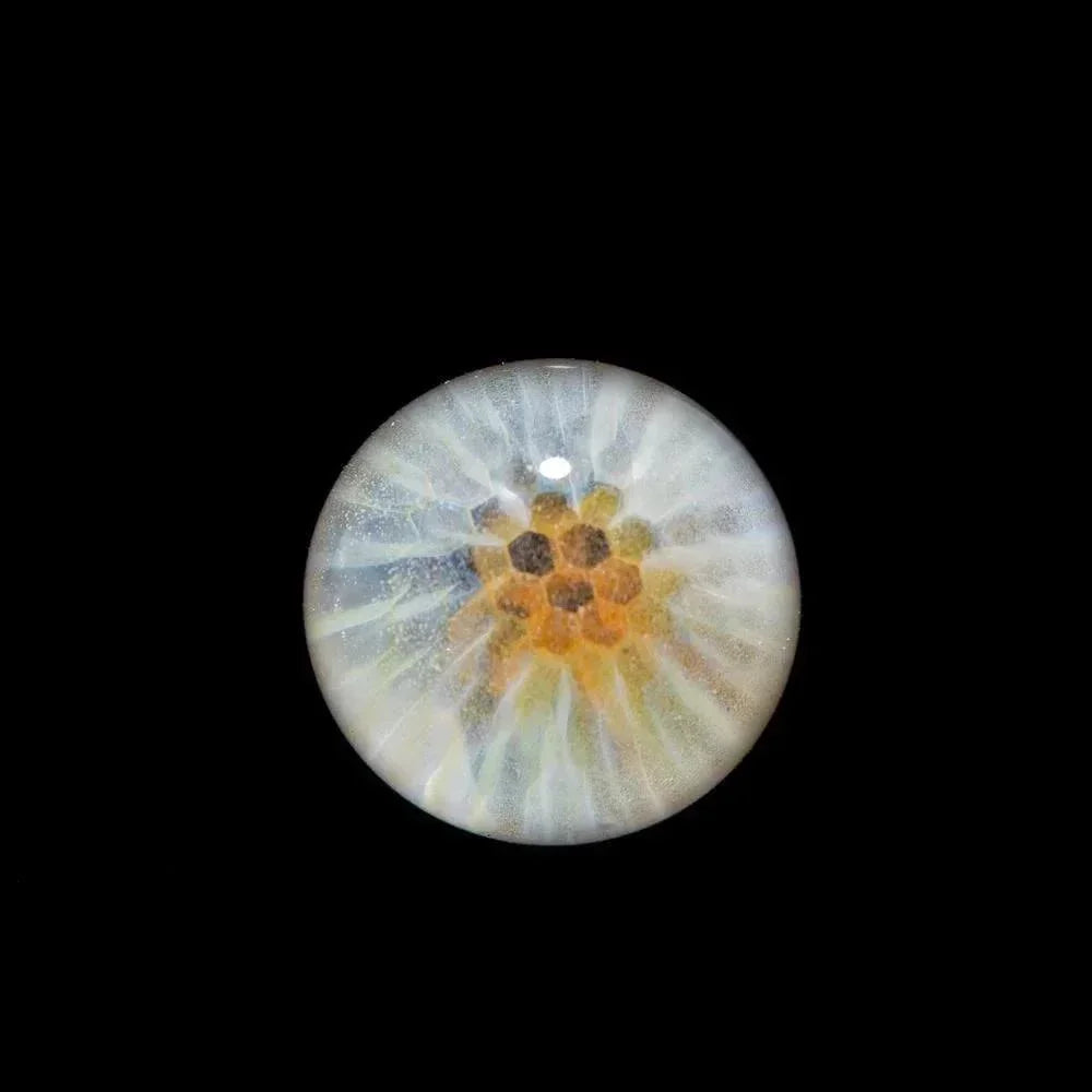Handcrafted glass marble with honeycomb pattern and iridescent details on black background