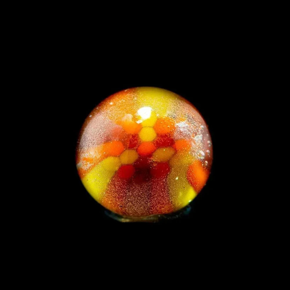 Close-up of a colorful glass marble with yellow, orange, and red hexagonal patterns