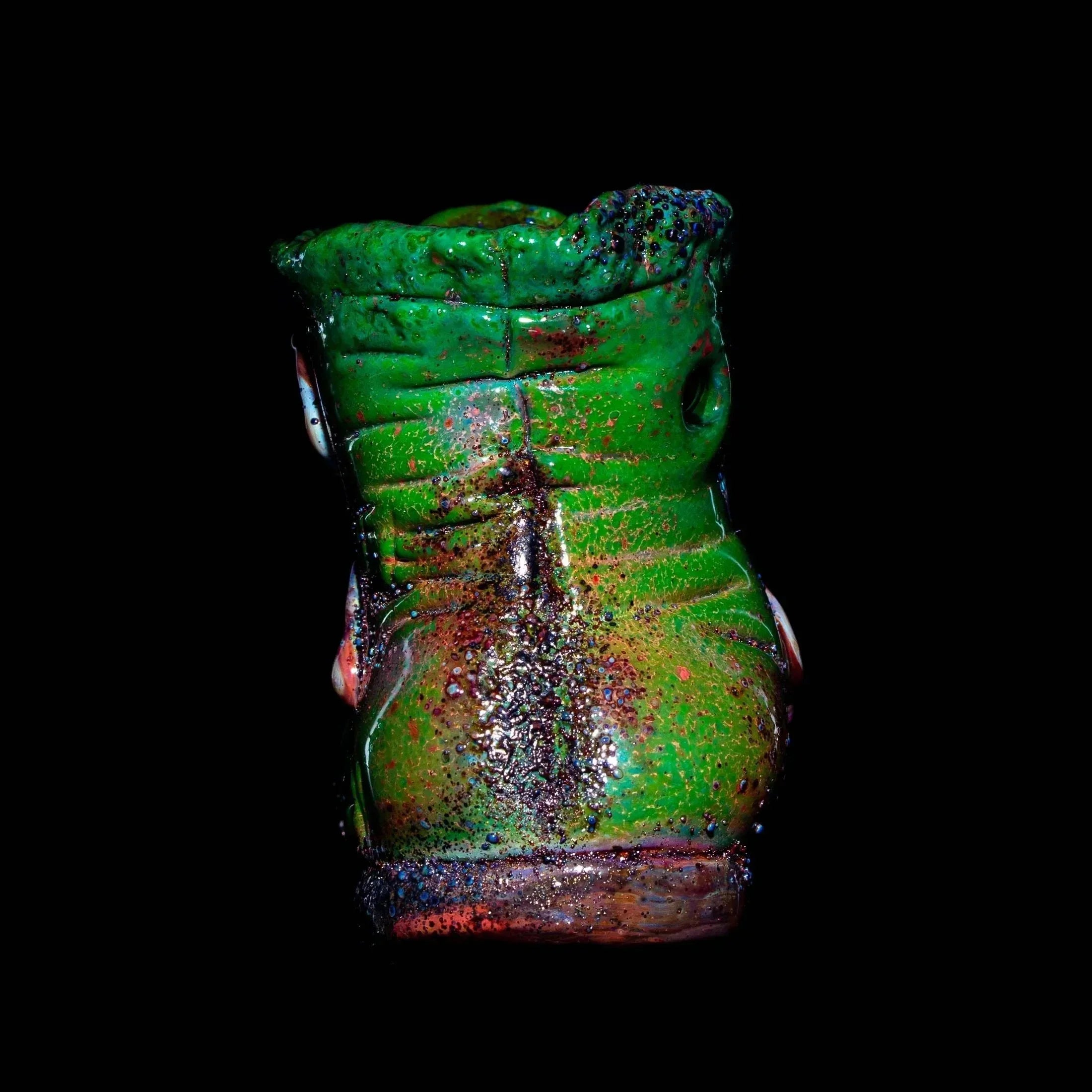 Green glass boot hand pipe with textured details on black background
