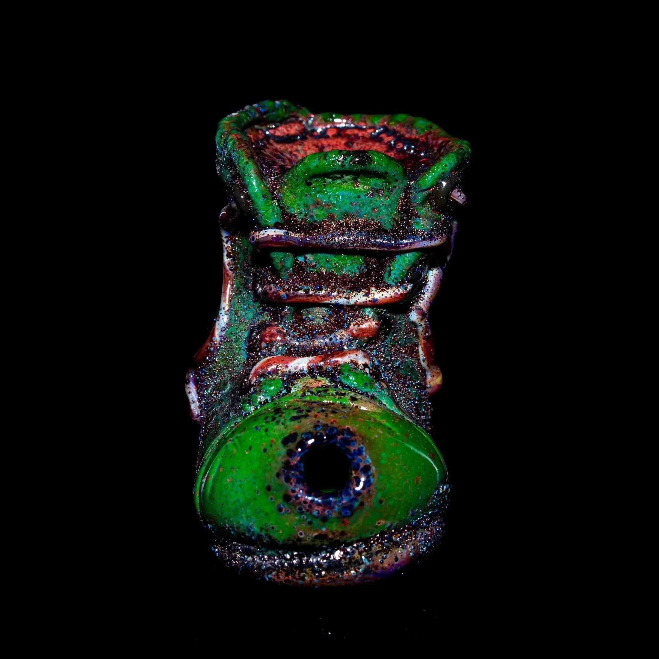 Colorful glass pipe shaped like a boot with green and red detailing on black background