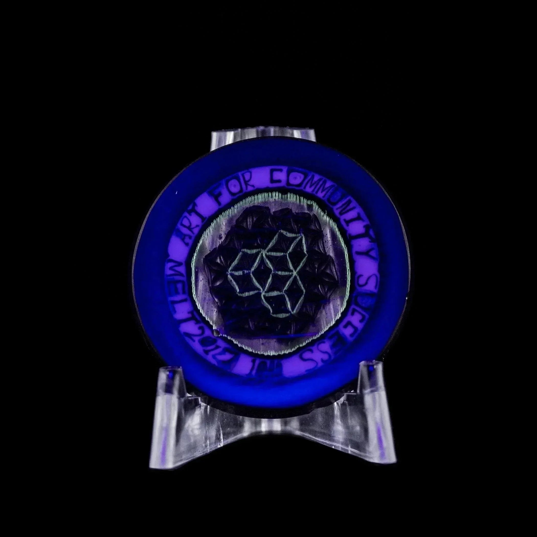 Glowing blue glass disc with geometric art and 'Art for Community Success' text on stand