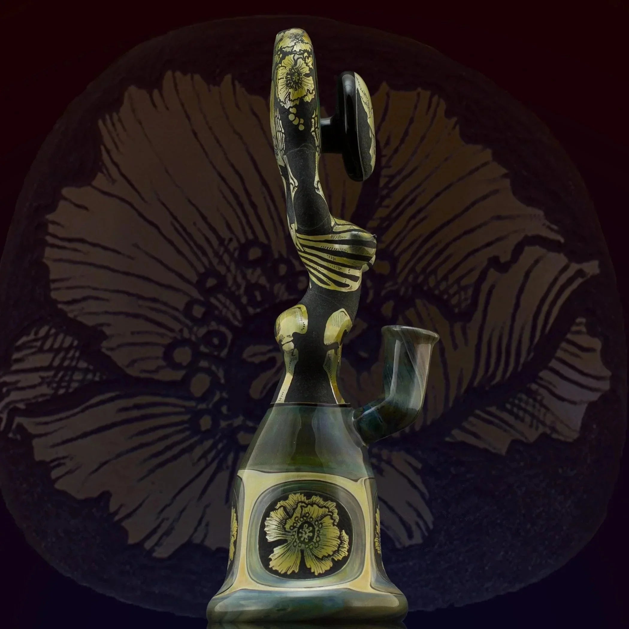 Artistic glass water pipe with gold floral engravings on a dark background