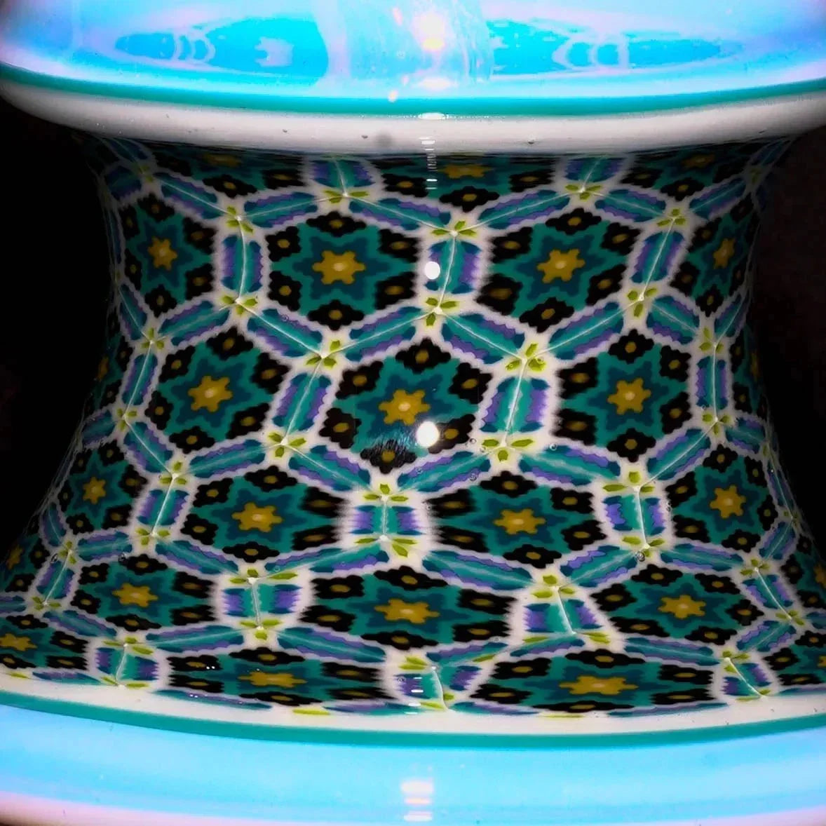 Close-up of a glass pipe neck with intricate geometric millefiori pattern and vibrant colors