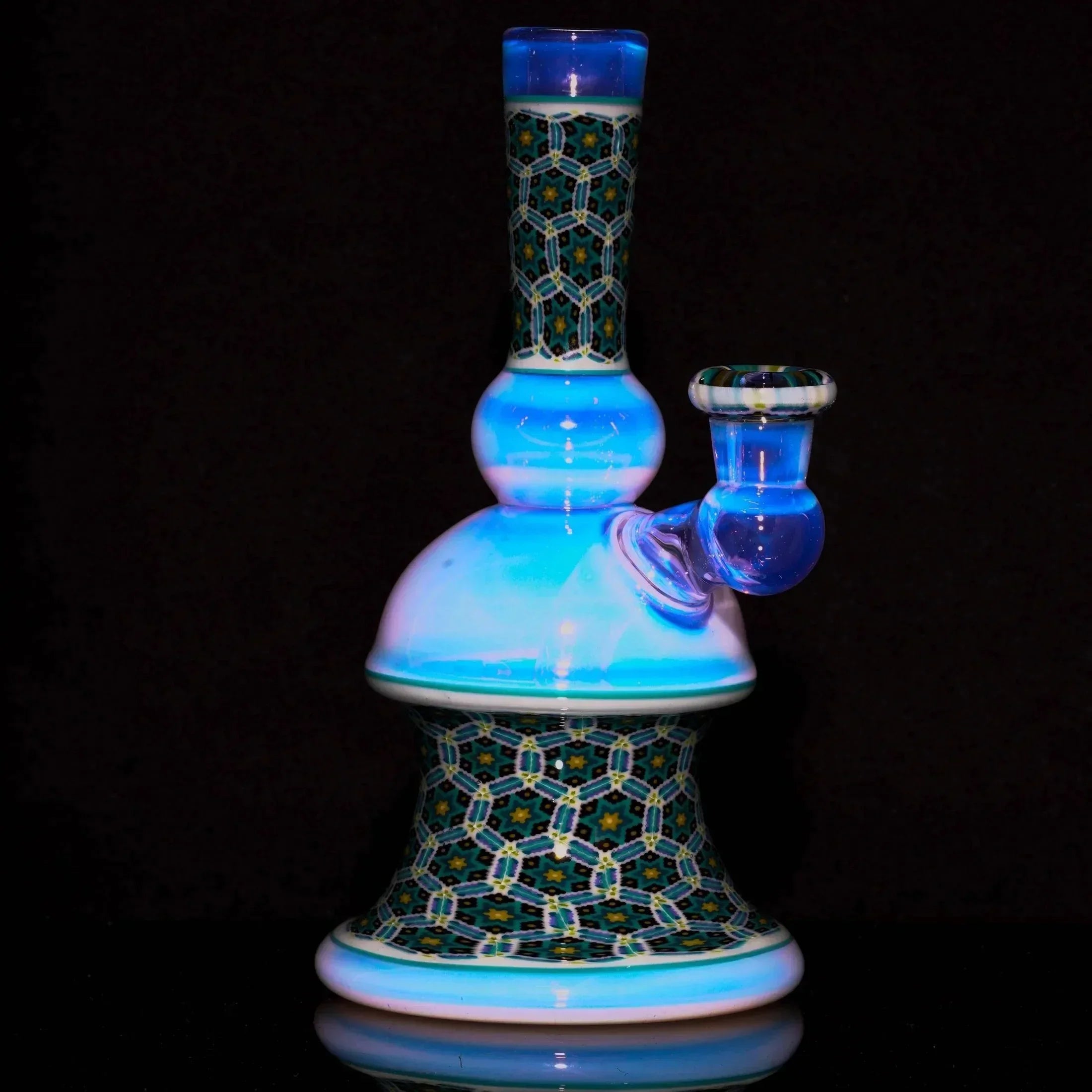 Heady glass water pipe with intricate geometric patterns and blue accents on black background