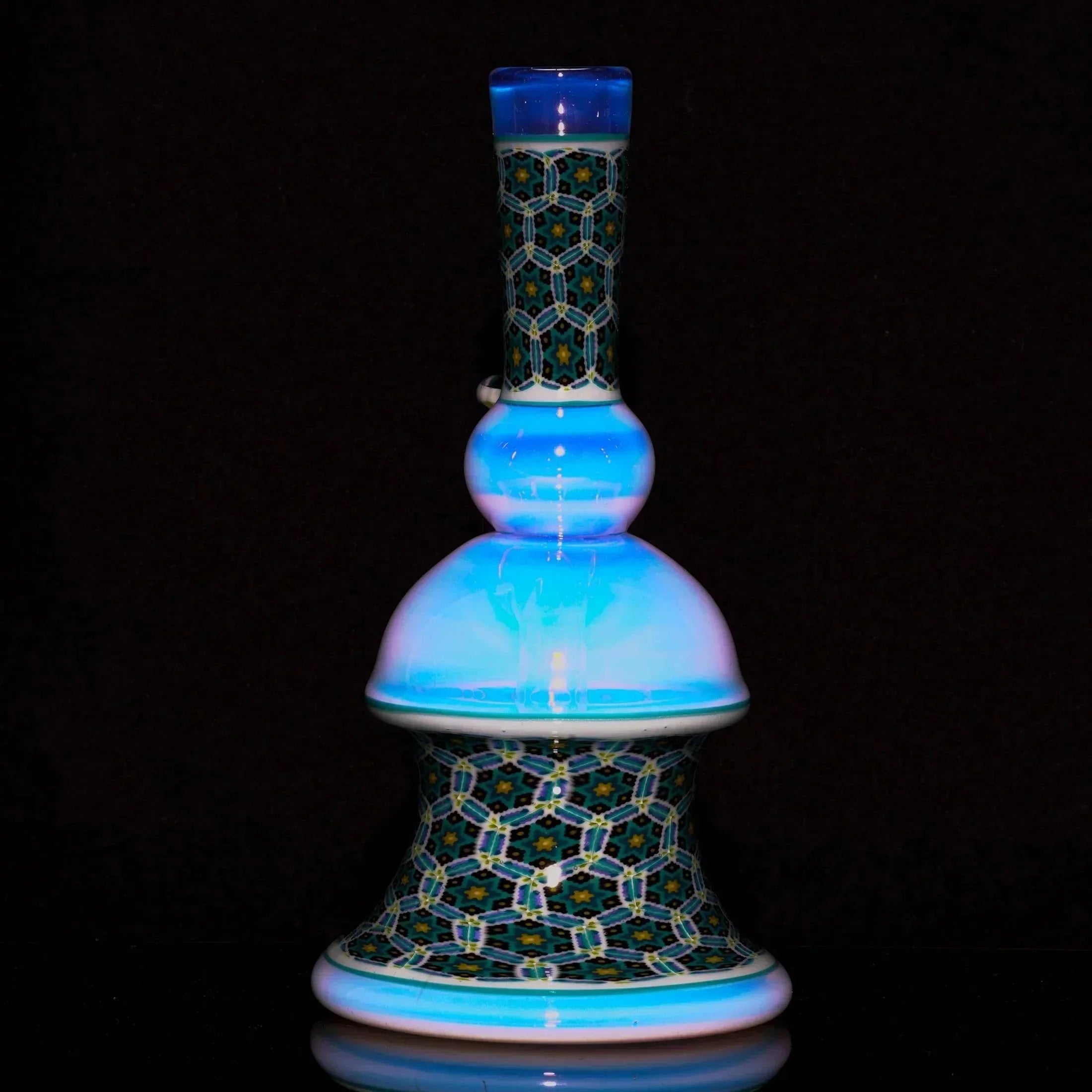 Intricate glass water pipe with blue accents and geometric patterned base on black background