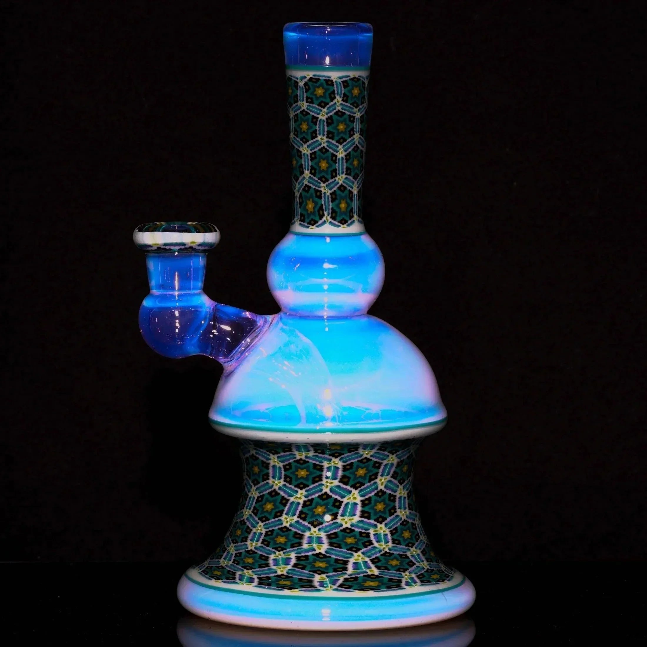 Intricate glass water pipe with blue, white, and geometric patterned accents on black background