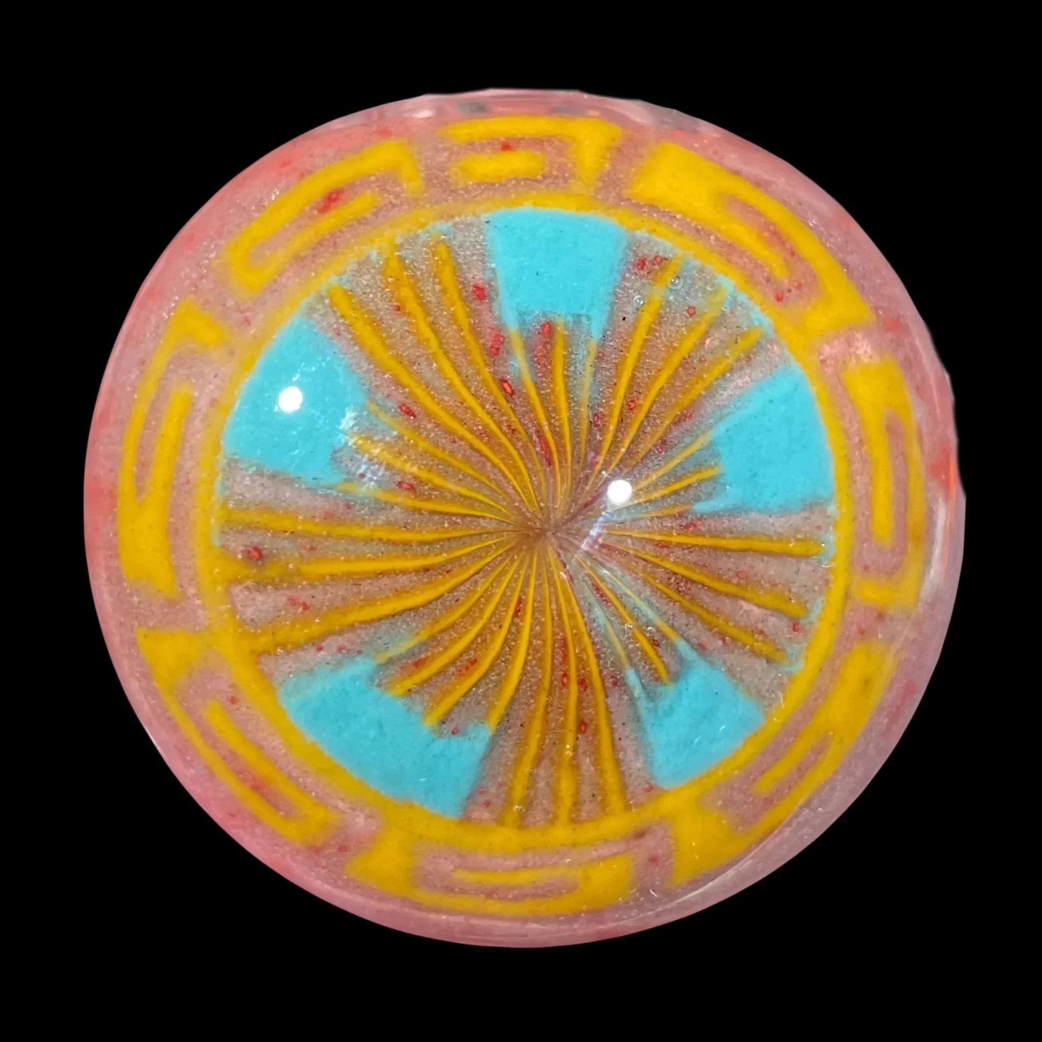 Colorful glass marble with yellow, blue, and red intricate patterns on black background