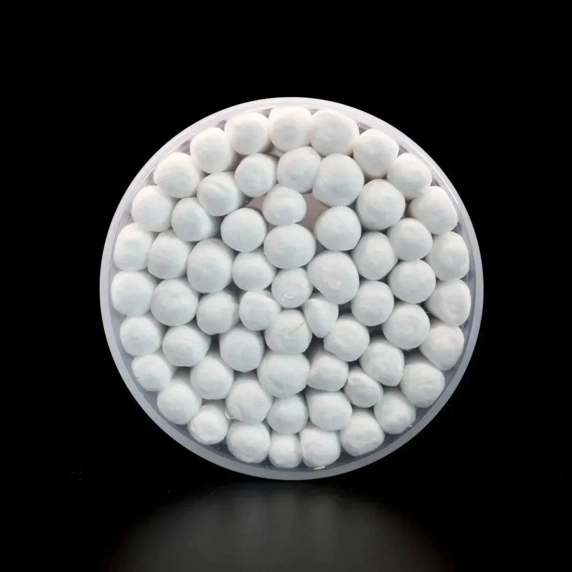 Round container filled with white cotton cleaning balls on a black background
